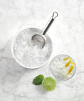 Secchiello ghiaccio con paletta in acciaio inox, cocktail con lime e menta su superficie marmo, perfetto per bar casalingo